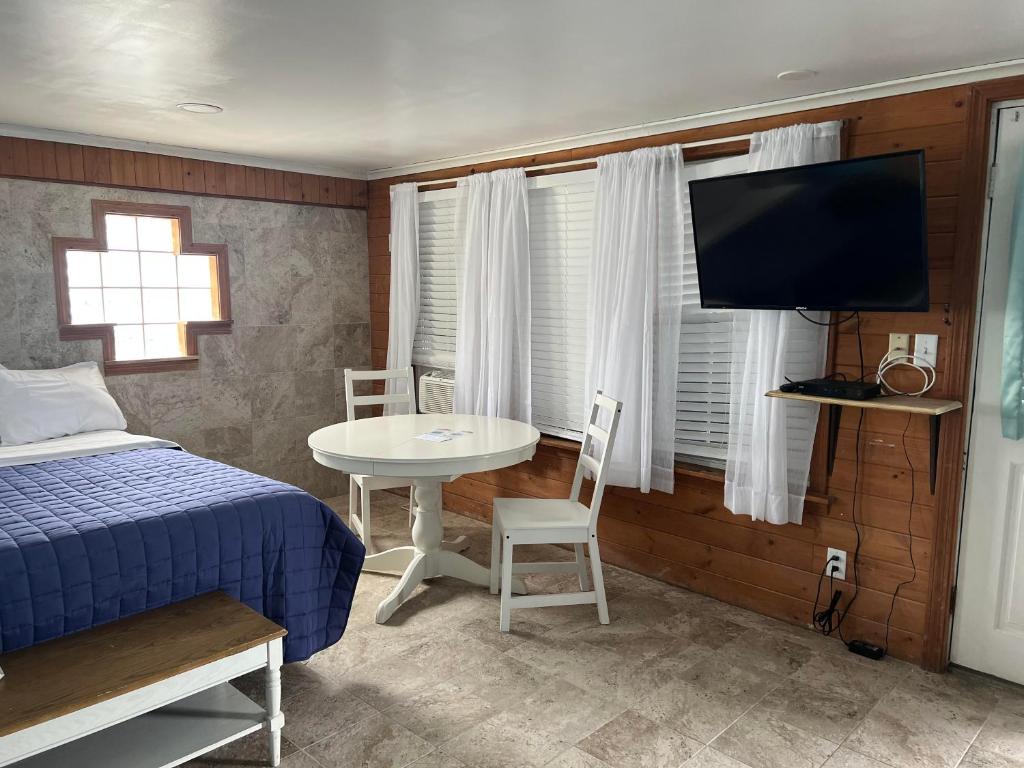 汉普顿Nautical Motel的一间卧室配有一张床、一张桌子和一台电视。