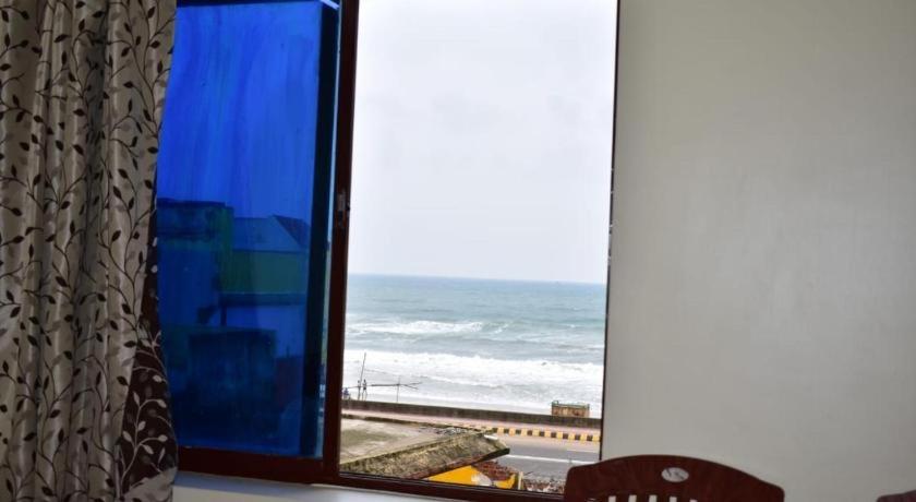 普里Hotel Lovely Palace ! Puri的窗户享有大海和海滩的景致。