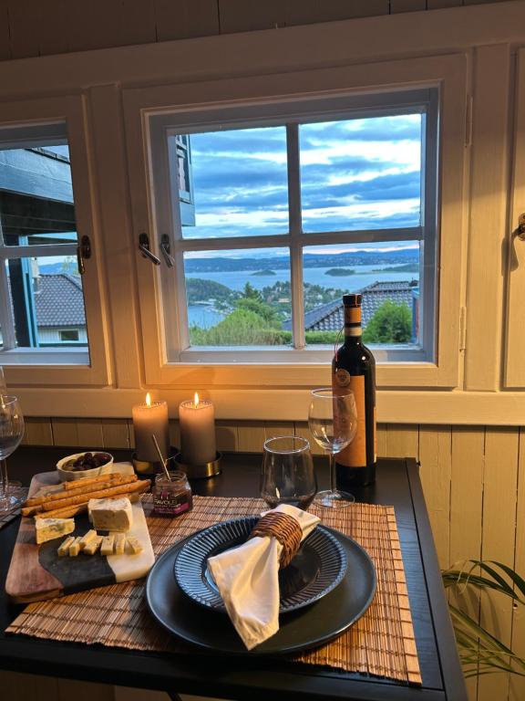 奥斯陆The View Guesthouse at Ekeberg -10 min by tram to Oslo S的一张桌子,上面放着一瓶葡萄酒和一盘奶酪