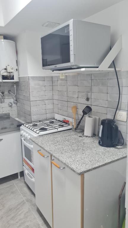 拉里奥哈Departamento cómodo的白色的厨房配有炉灶和微波炉。