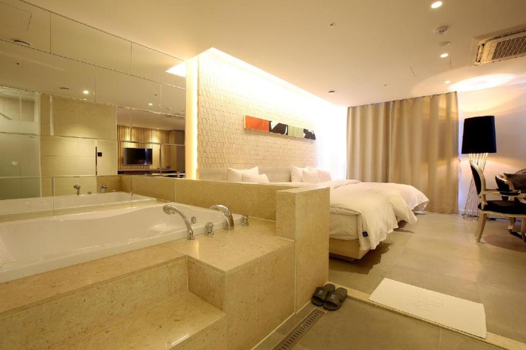 首尔Hotel Lassa的一间带浴缸和床的浴室以及一间卧室