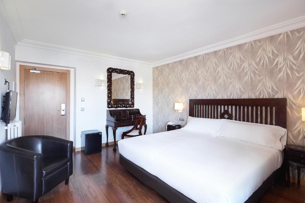 菲格拉斯Sercotel Hotel President的一间卧室配有一张床、一把椅子和镜子