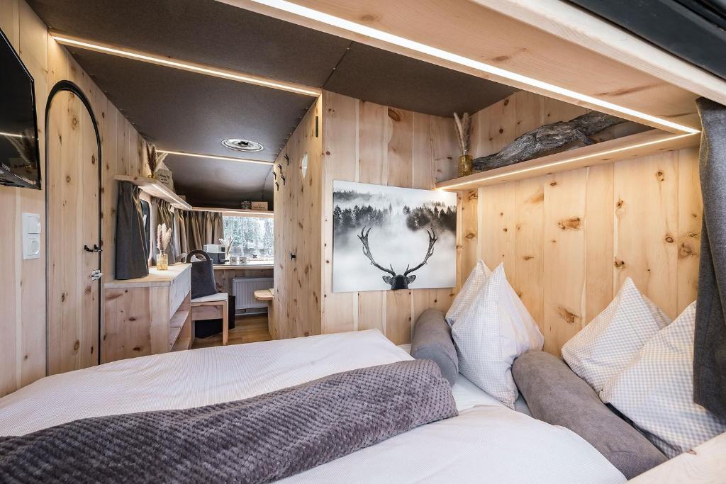 新波南特Mountain Caravan - Zirben Nestl的卧室配有一张床铺,位于带木墙的房间内