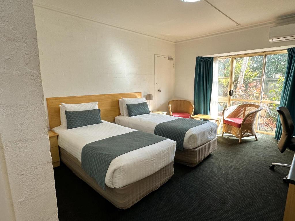 米塔贡Grand Country Lodge Motel的酒店客房设有两张床和窗户。