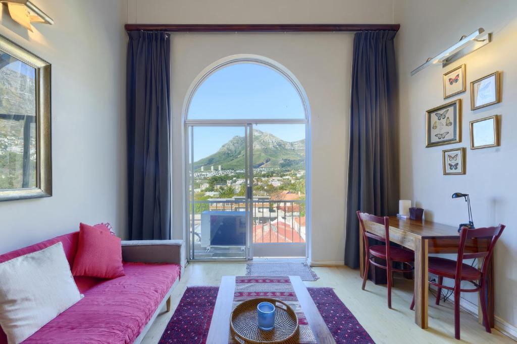 开普敦Loft Apartment off Kloof with Table Mountain views的客厅配有红色的沙发、桌子和窗户