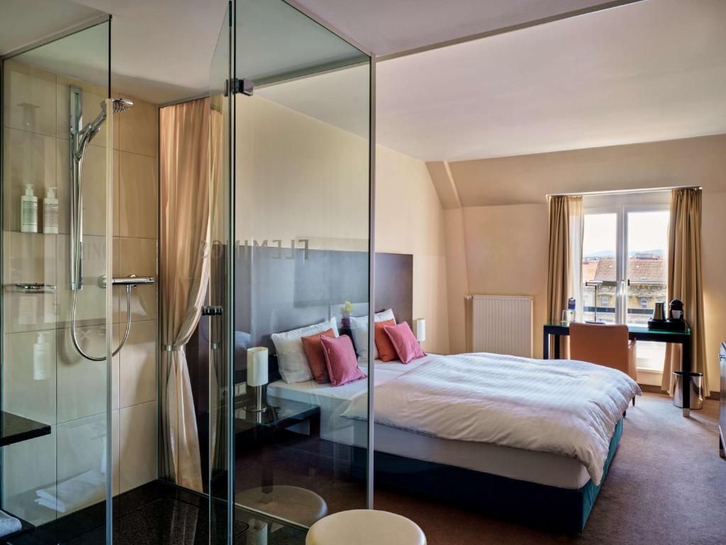 维也纳Flemings Hotel Wien-Stadthalle的一间卧室设有一张床和一个玻璃淋浴间