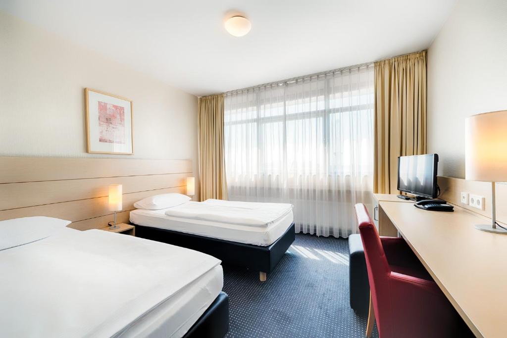 柏林Enjoy Hotel am Studio的酒店客房设有两张床和电视。