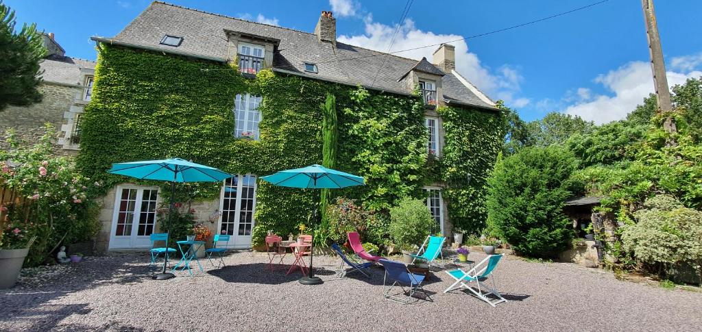 塔登La Vallée du Launay的房屋前面有椅子和遮阳伞
