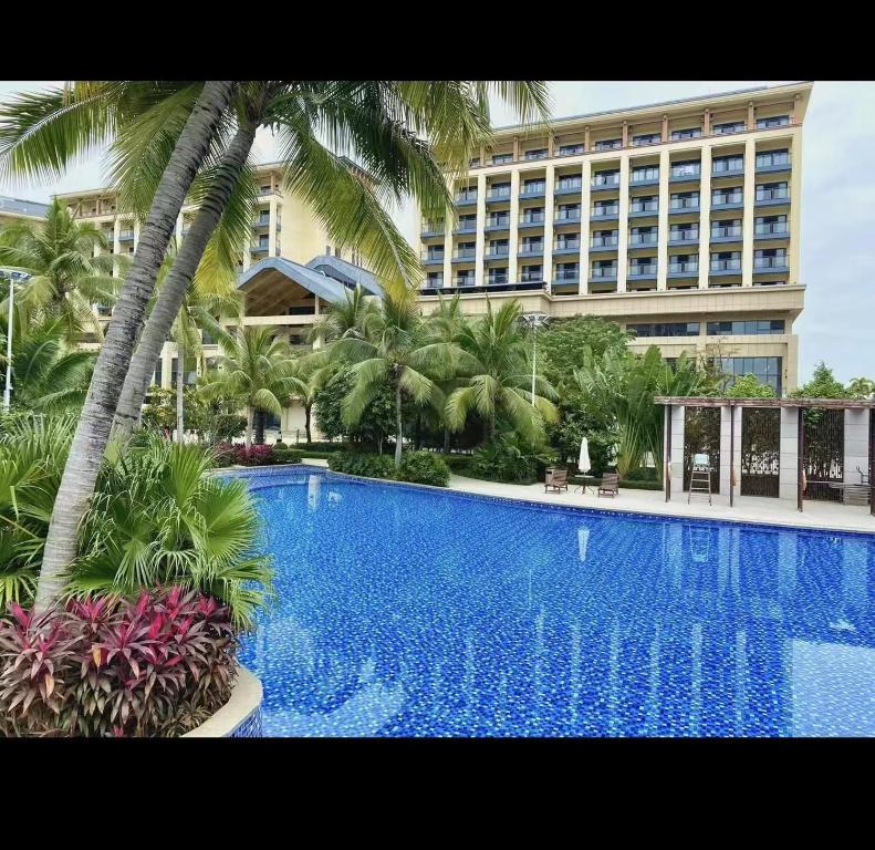 三亚中州国际公寓(三亚湾凤凰机场店)的大型酒店,设有棕榈树大型游泳池