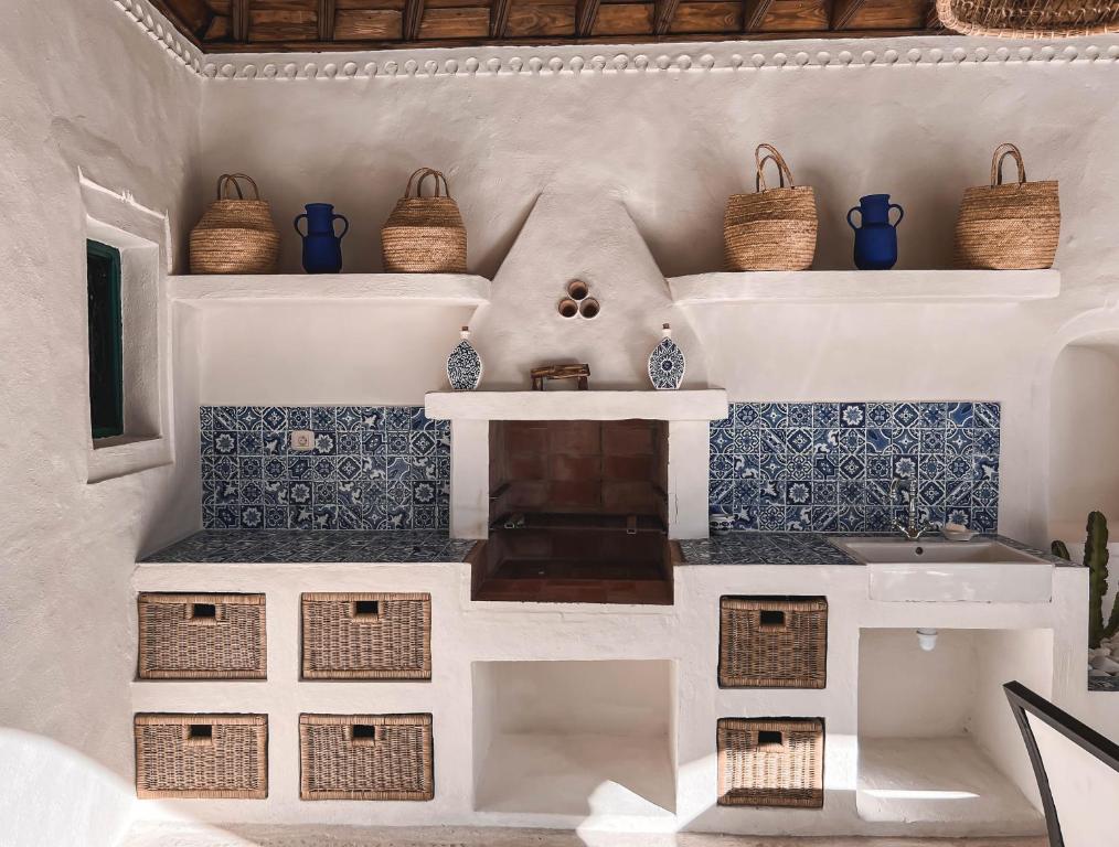 乌姆苏克Dar Naël的厨房铺有蓝色和白色的瓷砖,配有篮子