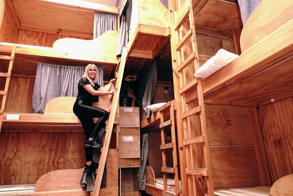 伊基克Aotea Hostel Iquique的坐在梯子上的女性,坐在带双层床的房间