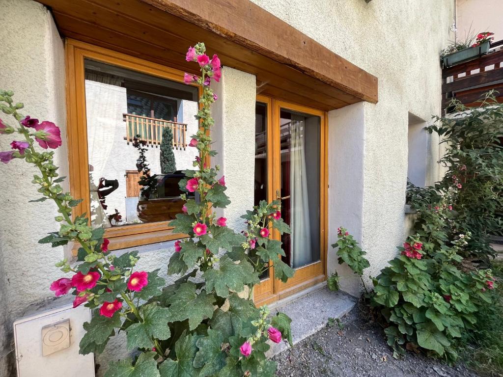 勒布罗伊斯The Stable House Bourg d’Oisans -bike/hike/ski的一座房子的窗户,上面有粉红色的花朵
