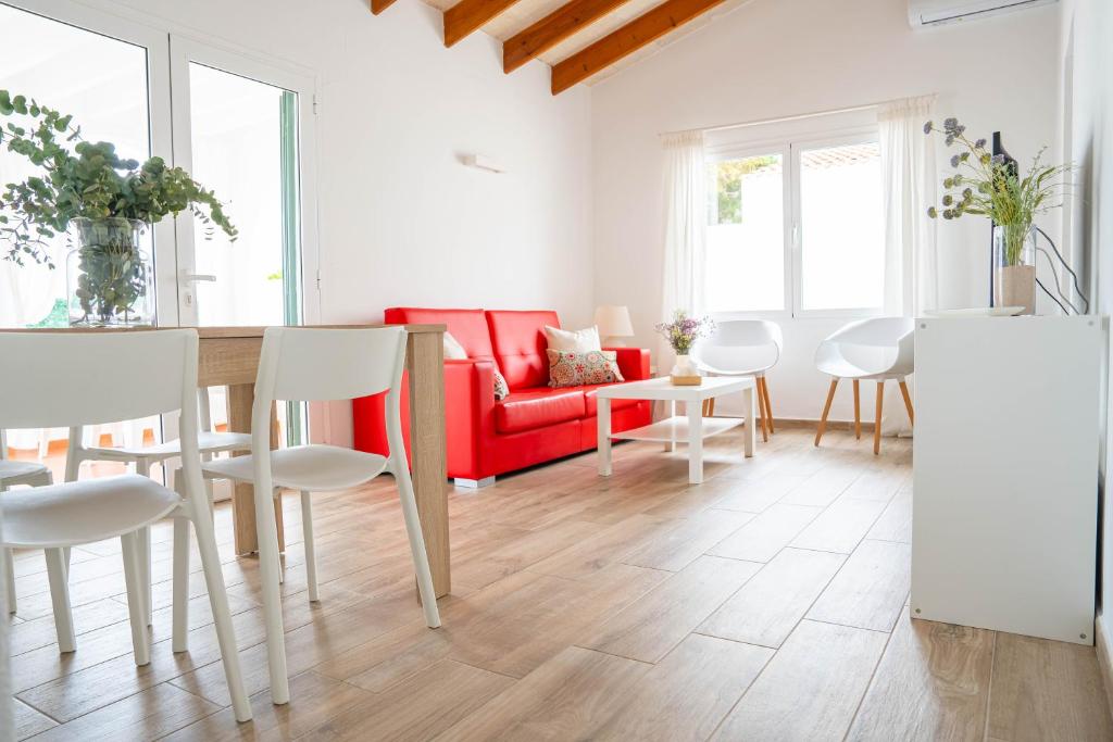卡兰博希Apartamento Calan Bosch, Ciutadella的客厅配有红色沙发和白色椅子