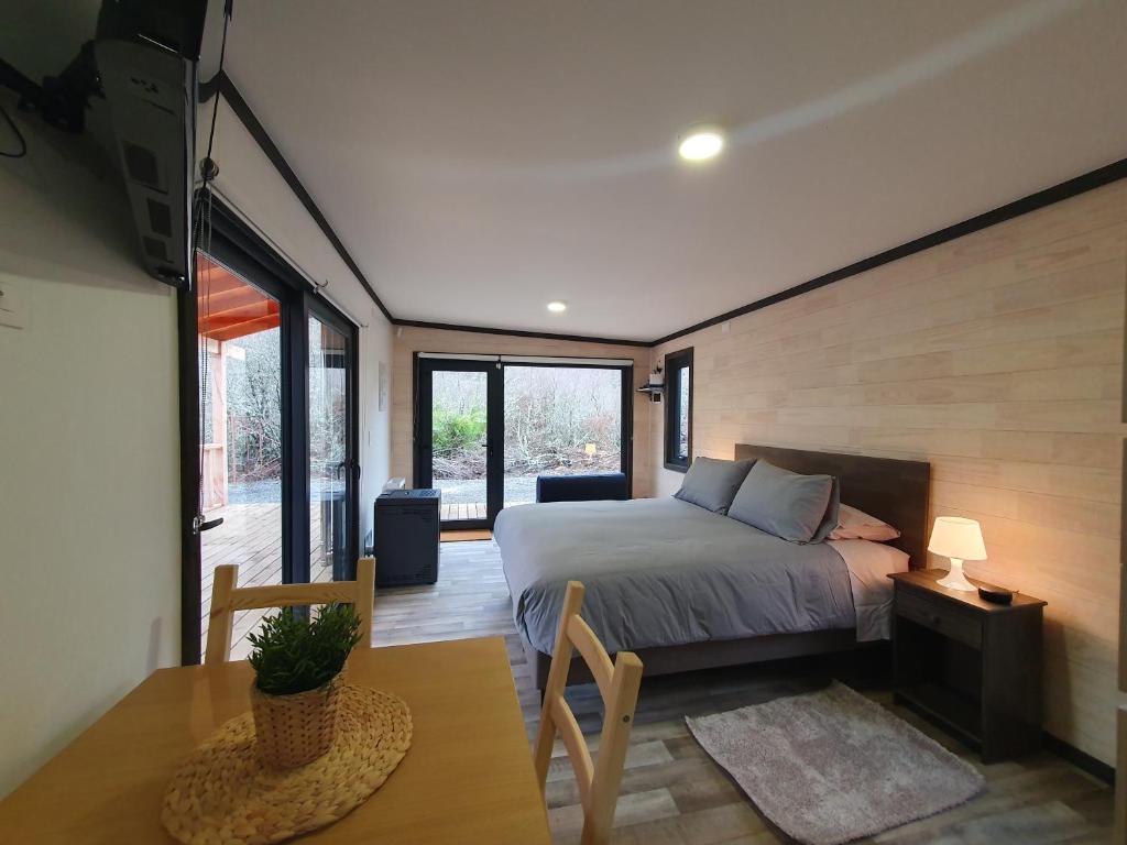 马拉卡韦罗Tiny House Suite Los Mallines de Malalcahuello的一间卧室配有一张床、一张桌子和一些窗户