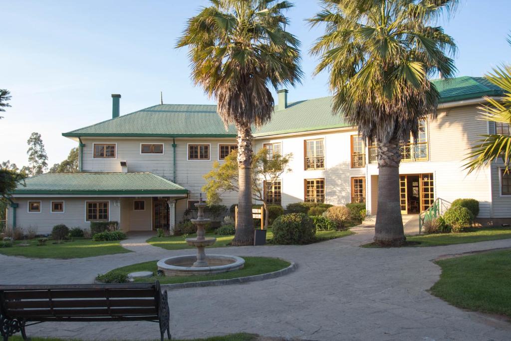 埃尔基斯科Hotel y Cabañas Huallilemu Sur - Caja Los Andes的一座棕榈树建筑,前面设有长凳