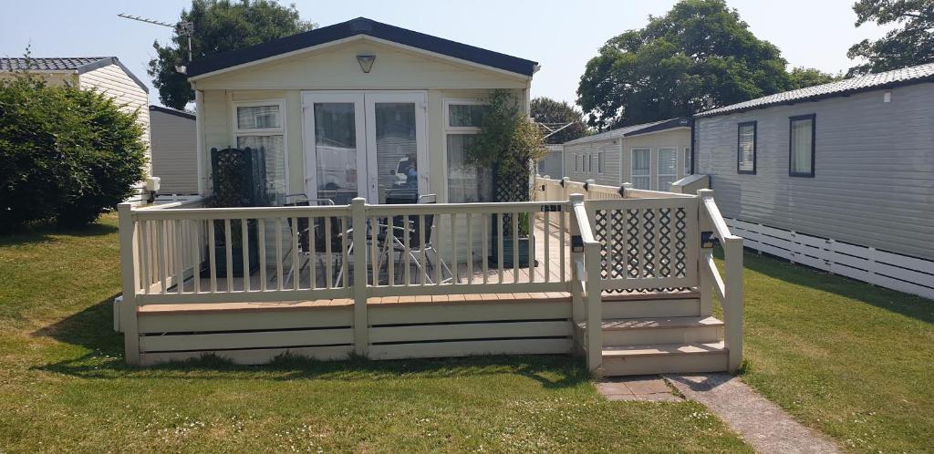 佩恩顿2 bed pet friendly caravan at Hoburne Devon Bay with decking的一座带门廊和围栏的小房子