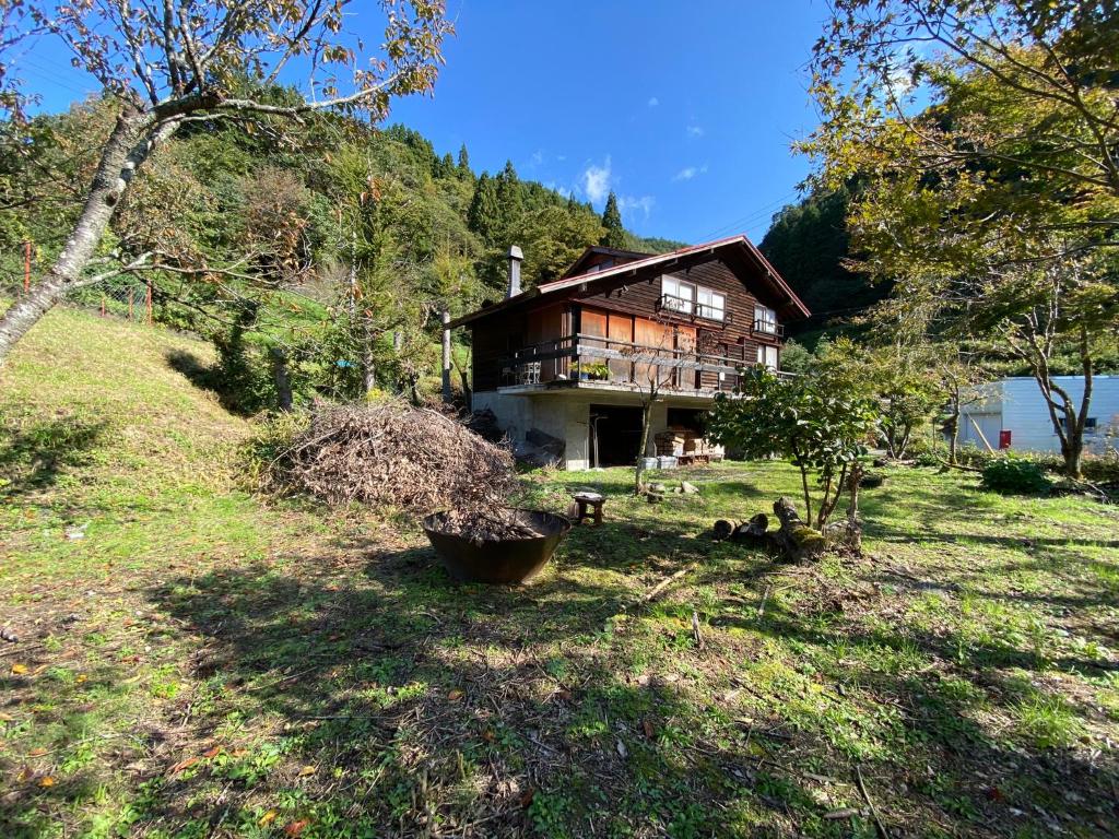Muraokakakayama hutte的坐落在郁郁葱葱的绿色田野上的房子