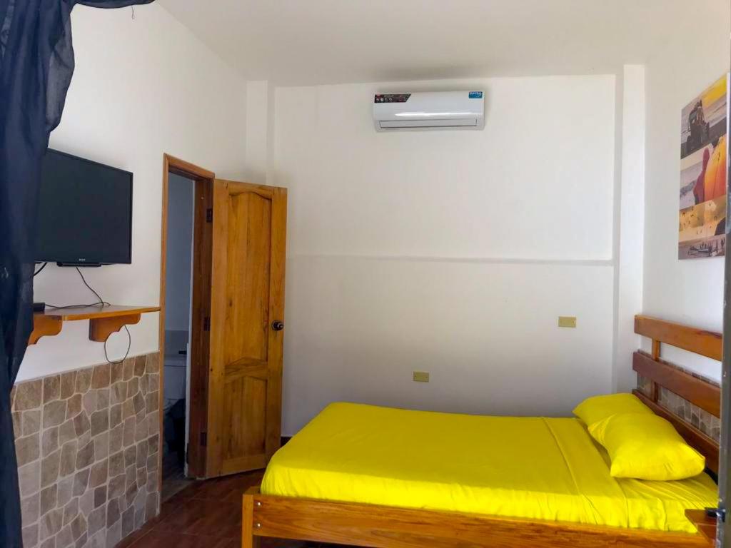 洛佩斯港COLIBRI GUEST HOUSE的一间小卧室,配有黄色的床和电视