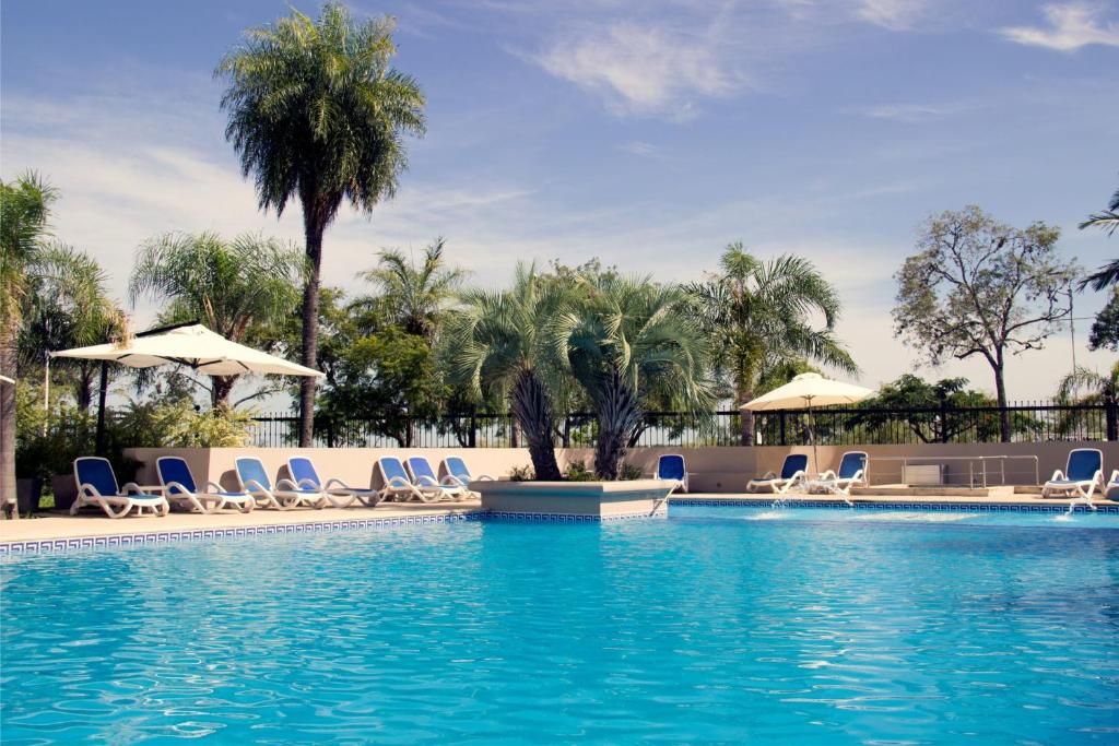 科连特斯卡西诺赌场旅游酒店的度假村内带椅子和遮阳伞的游泳池