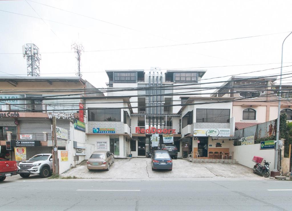General TriasRedDoorz RJs Bldg near Lyceum Gen Trias Cavite的一条城市街道,汽车停在建筑前