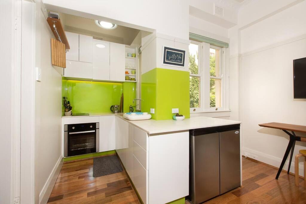 悉尼Tranquil 1 Bedroom Apartment - Rushcutters Bay Self-Catering的厨房配有绿色和白色的橱柜和桌子