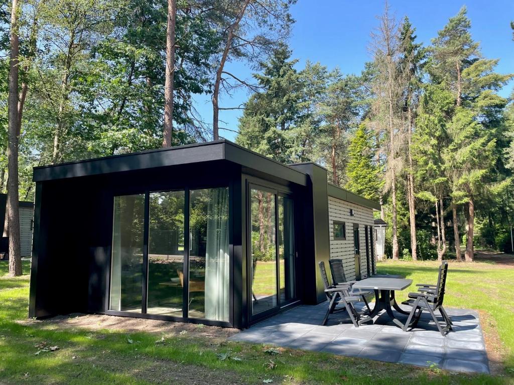 贝克贝亨Vakantiepark Hertenhorst的一间黑色的小房子,配有桌子和椅子