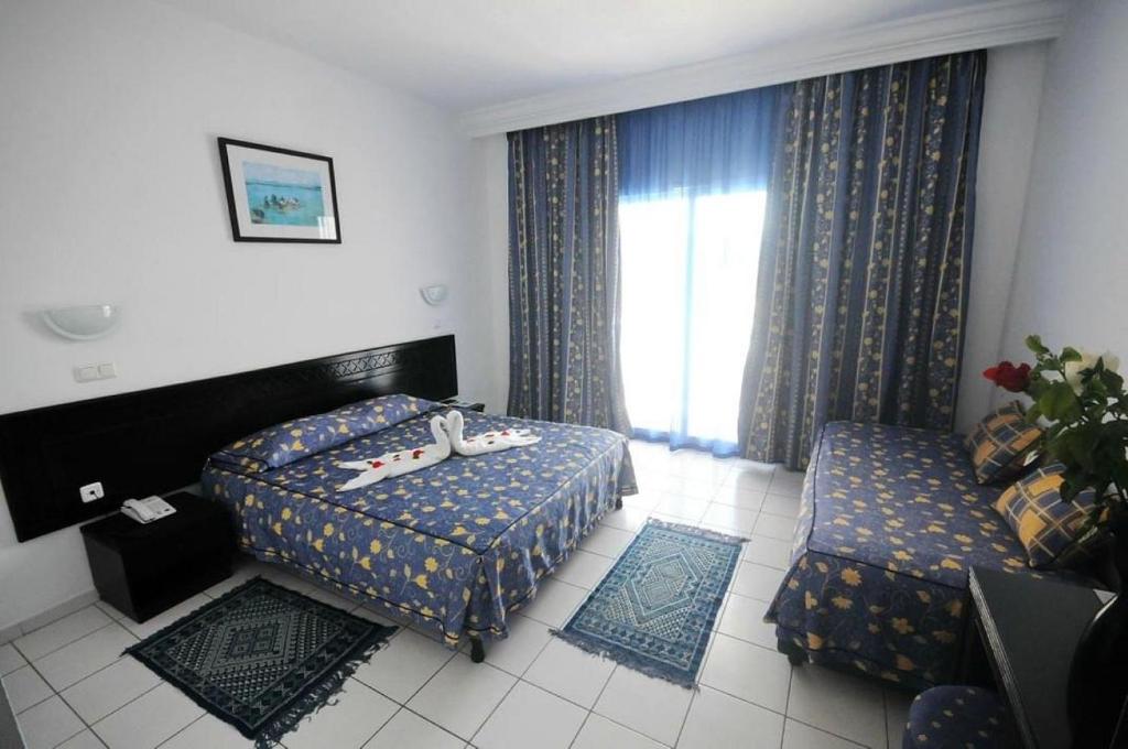 哈马马特Hôtel Mechmoum Yasmine Hammamet的酒店客房设有两张床和窗户。