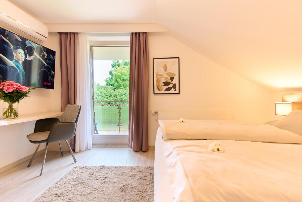 菲拉赫Pension - Ferienwohnungen Zollner的一间卧室设有两张床、一张桌子和一个窗口。