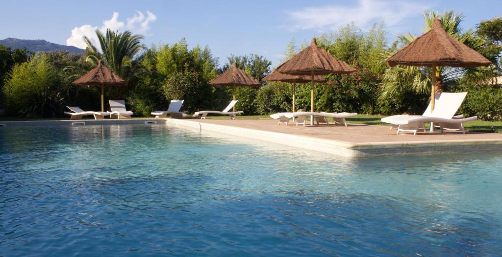 菲加里特拉科斯度假屋的毗邻度假酒店的带椅子和遮阳伞的游泳池