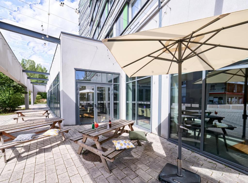 斯特拉斯堡斯特拉斯堡中心智选假日酒店的大楼前设有带长椅和遮阳伞的天井。