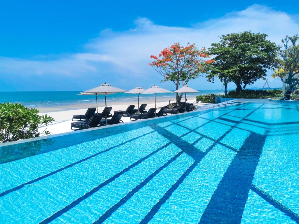 七岩斯攀瓦巴巴海滩俱乐部华欣酒店的海滩上带椅子和遮阳伞的游泳池