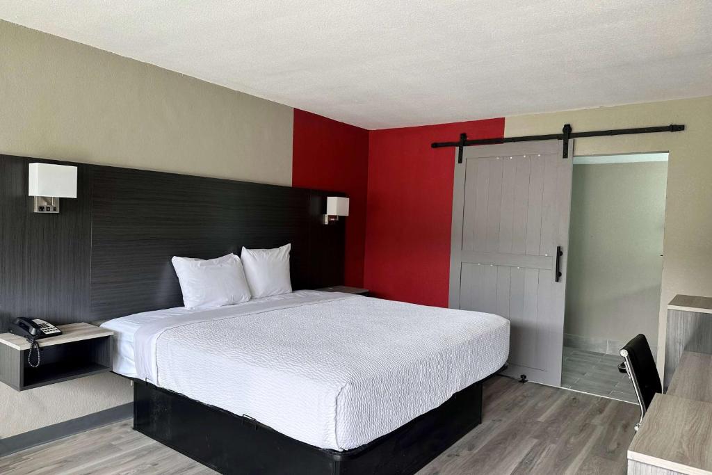 可可Ramada by Wyndham Cocoa的一间卧室设有一张大床和红色的墙壁