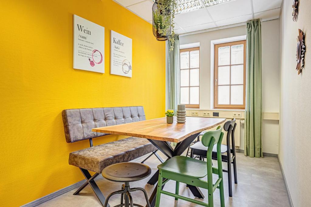 米尔豪森Pressehaus Apartment Obermarkt One的用餐室设有黄色的墙壁和一张木桌及椅子