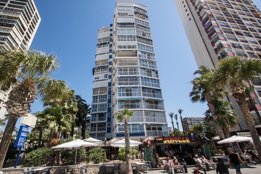 贝尼多姆托雷亚戈公寓酒店的一座高大的建筑,前面有棕榈树