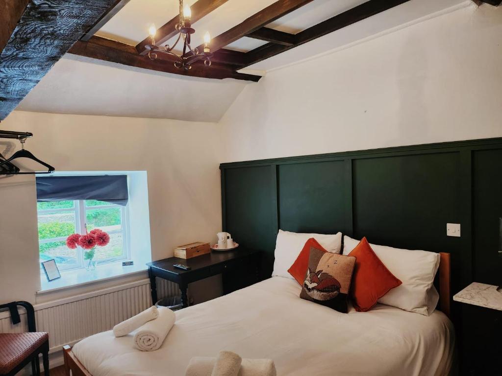 SouldernThe Fox Inn的一间卧室配有一张带绿色床头板的床和窗户