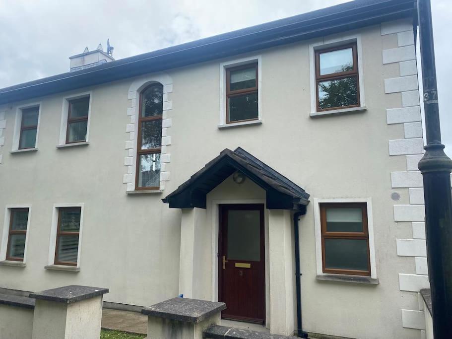 Beautiful 3 Bedroom House in Coolaney Village County Sligo的一间白色的房子,有红色的门和一根杆