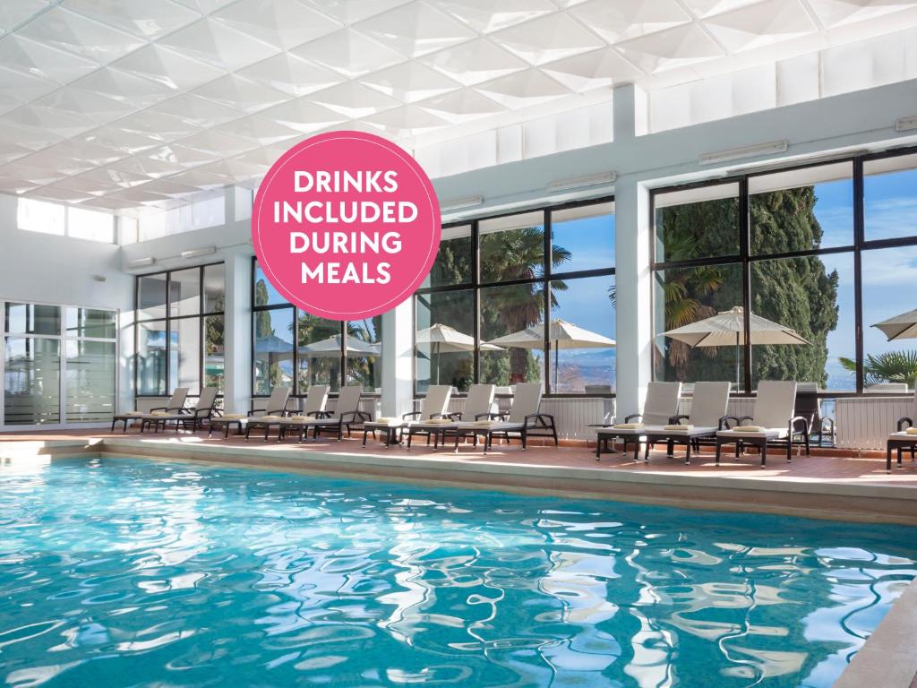 奥帕提亚Hotel Kristal - Liburnia的游泳池,上面有标志,上面写着用餐时邀请的饮料