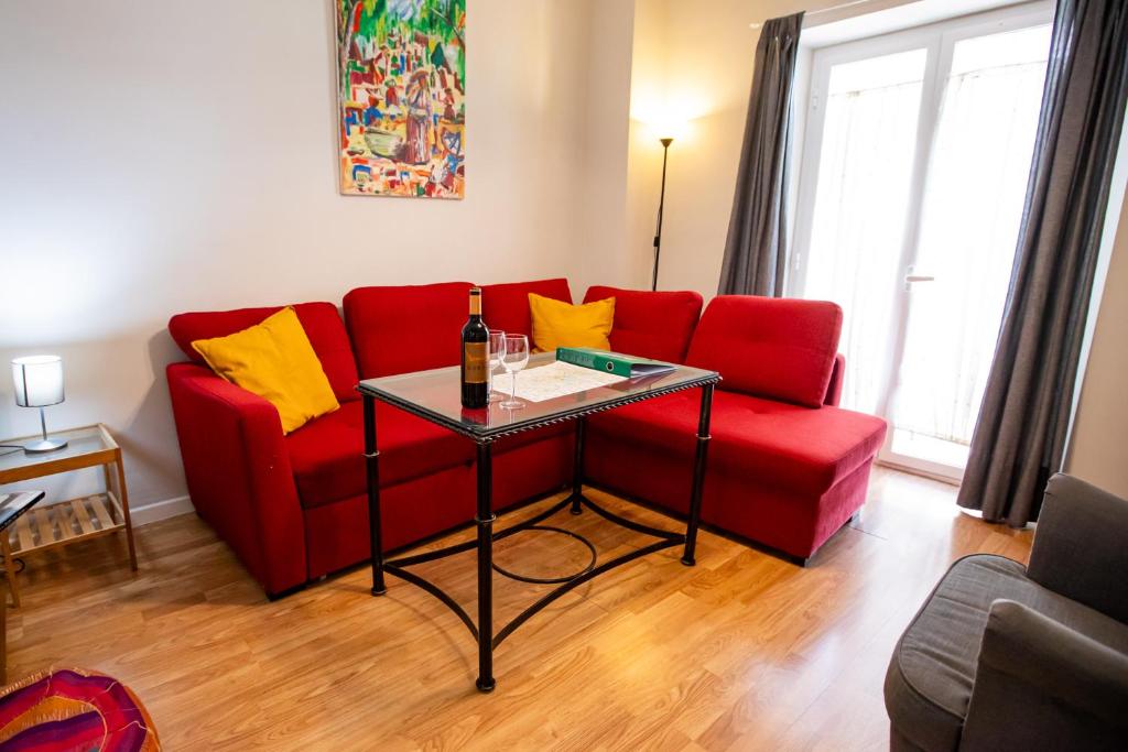 塞维利亚Apartamentos Doña Concha的客厅配有红色的沙发和玻璃桌