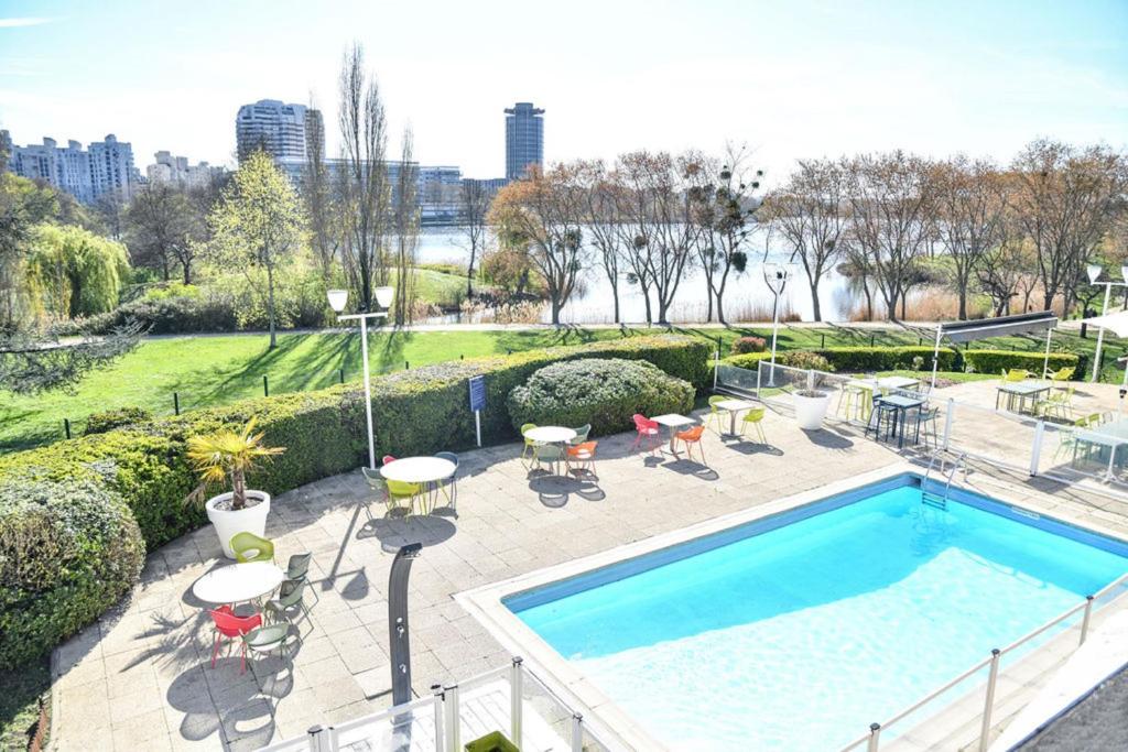 克雷泰伊诺富特巴黎克里特尔湖滨酒店的庭院内一个带桌椅的游泳池