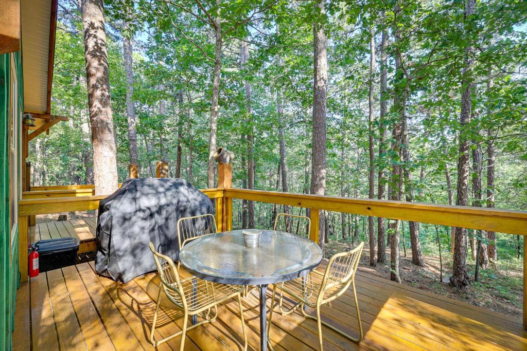 尤里卡斯普林斯Pet-Friendly Eureka Springs Rental with Private Deck的树木繁茂的甲板上设有带桌椅的天井。