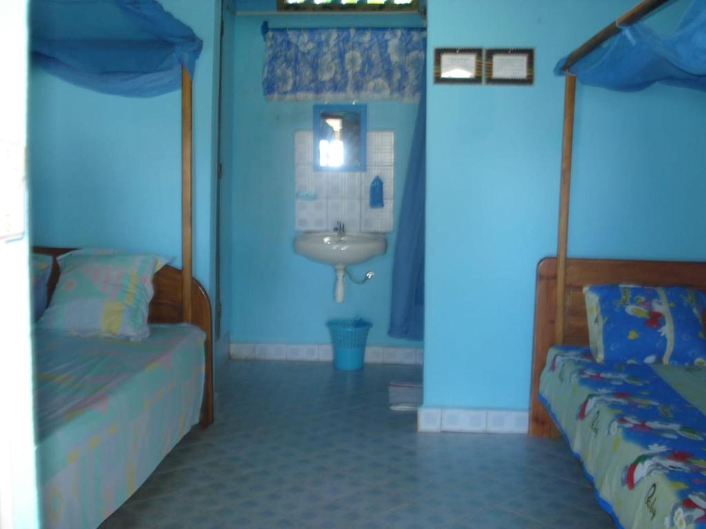 Bungalow le Charme, au bord de la mer的客房内的浴室设有两张床和一个盥洗盆。