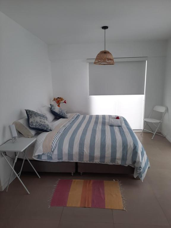 蓬塔赫尔莫萨Loft acogedor con área de parrilla y piscina的一间卧室配有一张床、一张桌子和一张地毯。