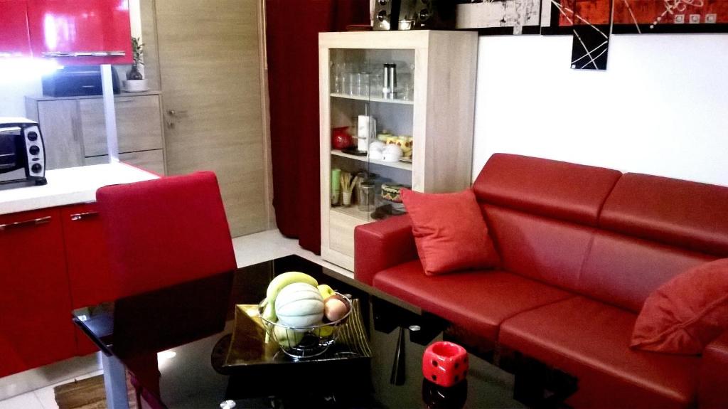 雷阿尔蒙特Appartamento Residence Canalotto的客厅配有红色的沙发和桌子