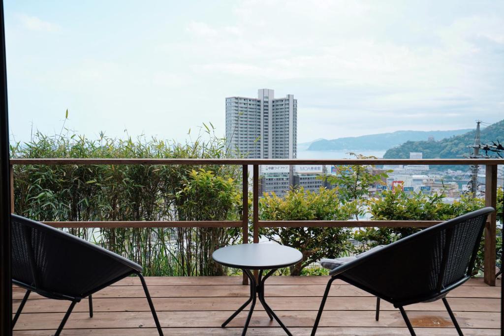 热海new! 熱海桃山邸　Atami terrace villa 〜Sauna & Onsen 〜的阳台的天井配有2把椅子和1张桌子