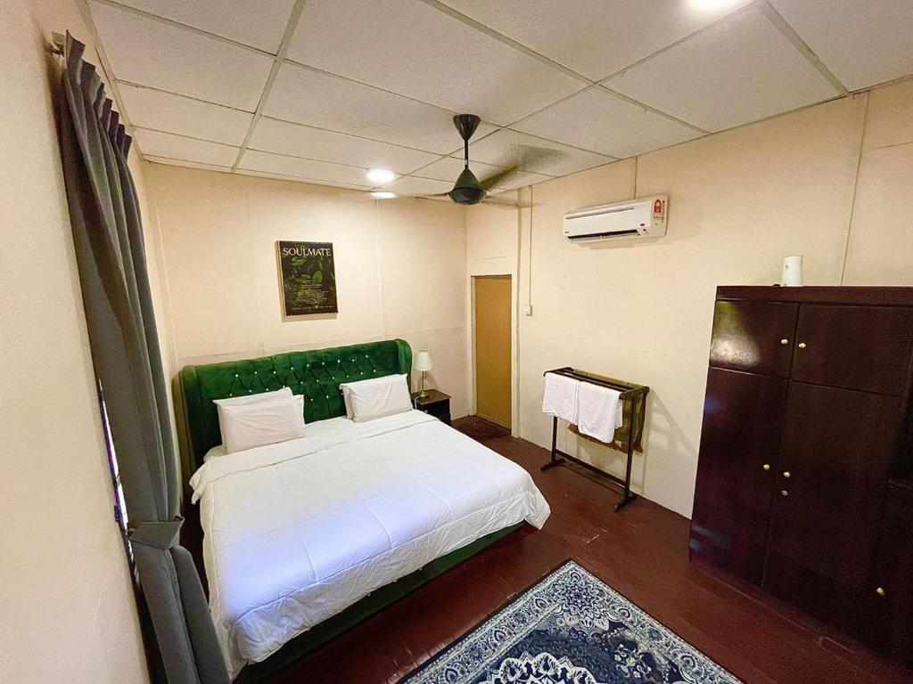 TumpatDGeting Beach Resort的一间卧室配有一张白色床和绿色床头板