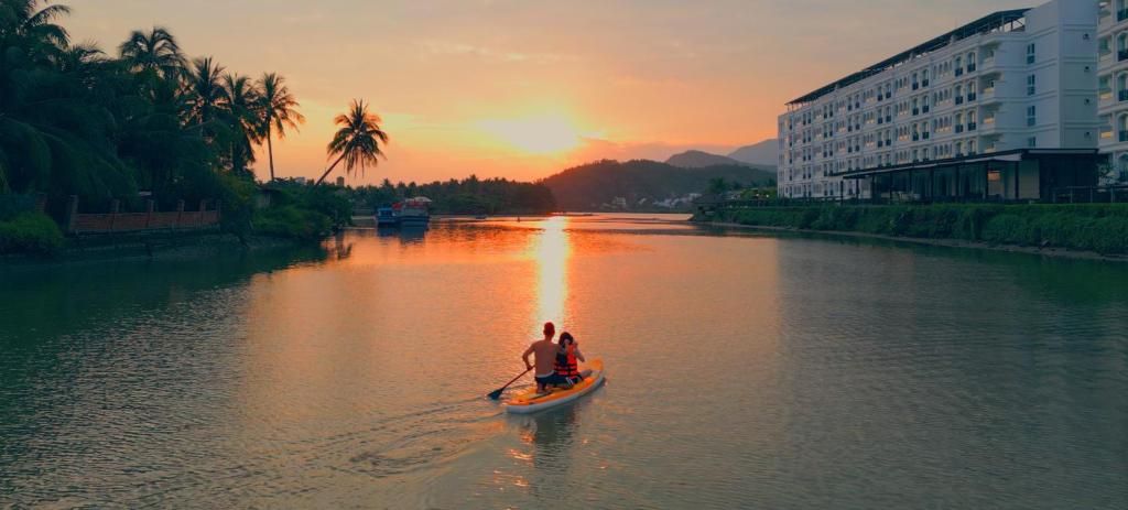 芽庄Champa Island Nha Trang - Resort Hotel & Spa的日落时分,两人在河边乘船