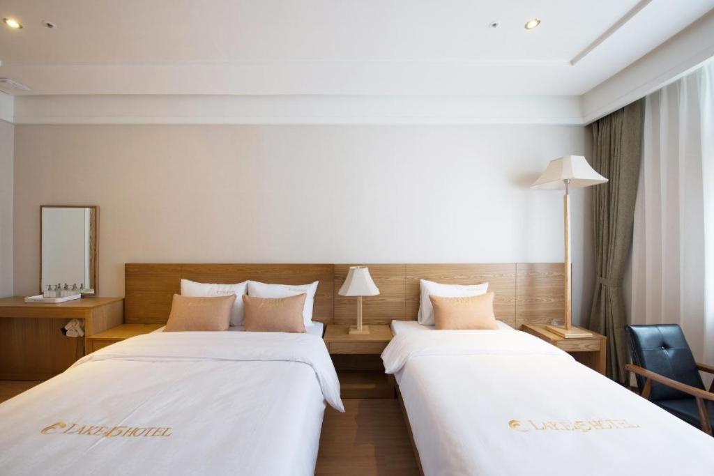 NajuLake 45 Hotel的配有白色床单的酒店客房内的两张床