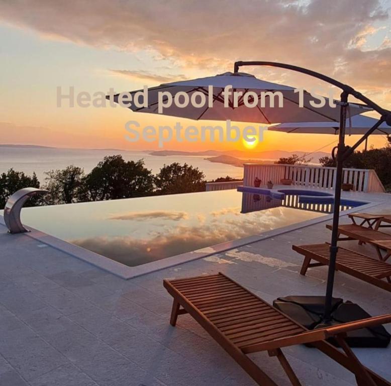 珀德垂那Sea view Luxury Hotel Villa Conte with private swiming pool and romantic SPA的日落时分,游泳池边设有长凳和遮阳伞