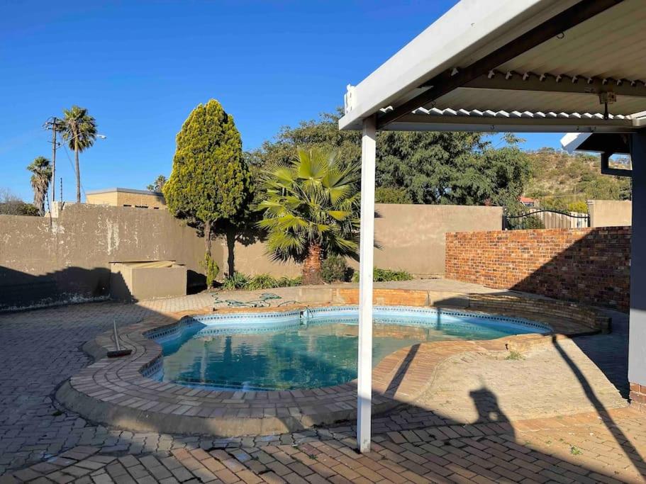 约翰内斯堡Home in Suideoord, Jhb south的庭院内的小型游泳池,配有遮阳伞