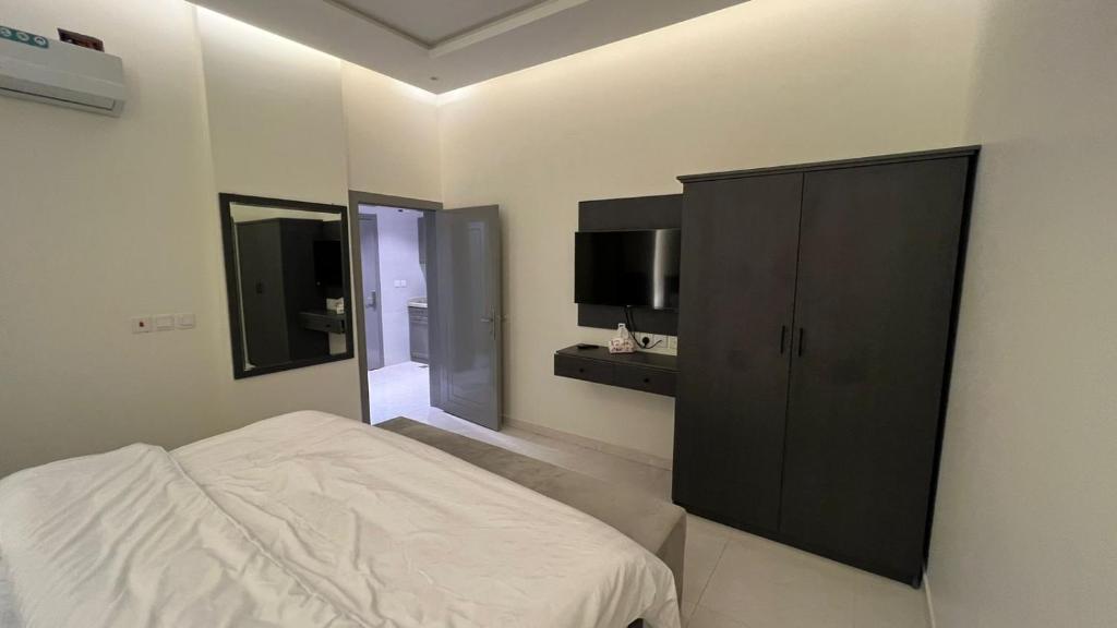 Mahlalشقق ميسم الورد للشقق المفروشه的一间卧室配有一张床和一个黑色橱柜